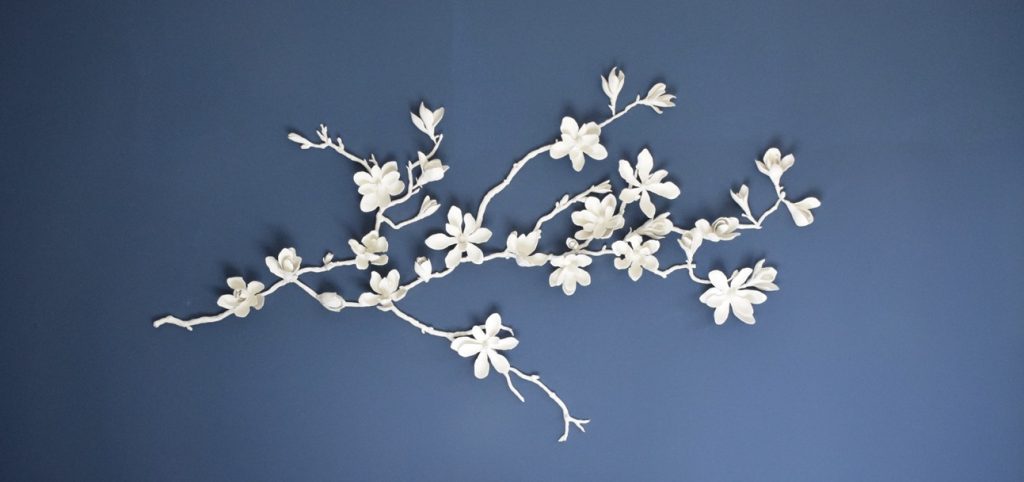 imagen de un mural de flores de ceramica sobre una pared azul oscuro de sai creamics